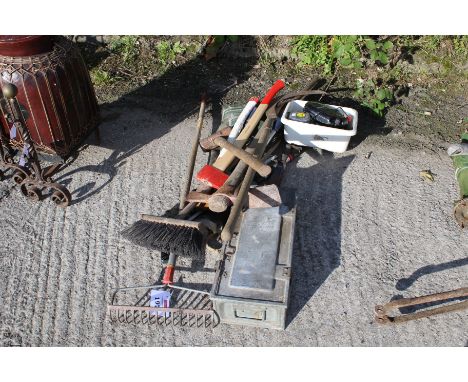 A collection of hand tools and an ammunition crate. Noting axes, a sickle, rake etc plus strimmer wire and waders etc.
