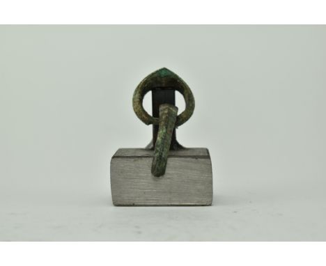 An Iron Age small bronze buckle with clasp, figured with engraved line decoration and pointed edge. Mounted on a recent metal