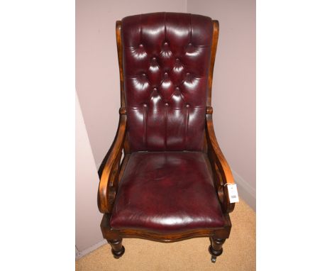 A Victorian walnut button-back arm chair upholstered in red leatherette, legs terminating in brass casters.
