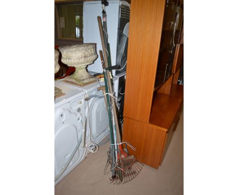 A bundle of garden tools, including: a rake; yard broom; and others.