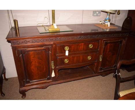 A large Victorian mahogany sideboard, blind fret carved frieze above two panel doors centred by two short drawers, open shelf