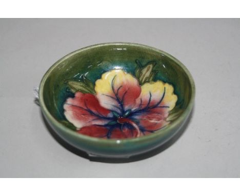 A MOORCROFT POTTERY FOOTED TRINKET DISH, 'Hibiscus' pattern, paper label to base, diameter approximately 9cm