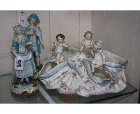 CONTINENTAL CERAMICS, comprising blue glazed male with violin and female with book on naturalistic bases with floral encruste