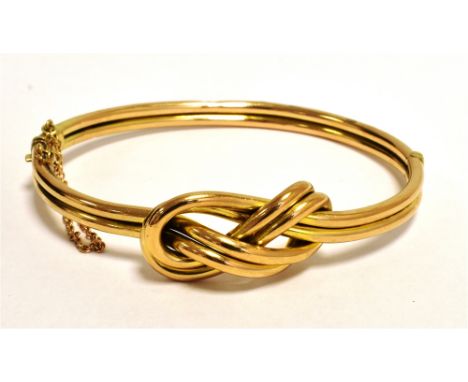 A STAMPED 9CT LOVERS KNOT BANGLE with push clasp and safety chain. Bangle diameter 6cm weight approx 9g