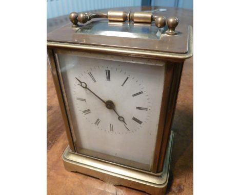A late 19th/early 20th century brass and glass-sided Carriage Clock, serpentine swing-handle and slightly raised upper sectio