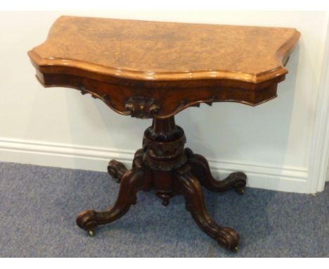 A good mid-19th century serpentine fronted figured walnut veneer foldover top Card Table, the frieze finely carved with a cen