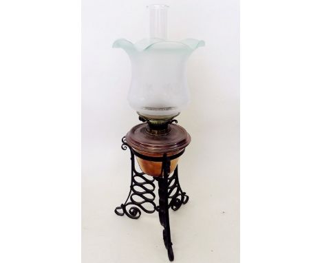 An oil lamp on wrought iron stand with etched green shade 