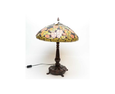 A 20th Century table lamp, the stained and leaded glass style shade decorated with fruiting foliage in autumnal hues, 62cms h