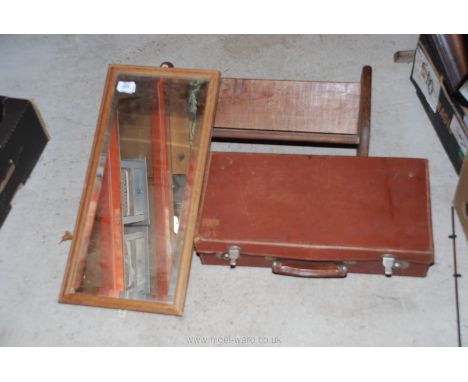 A wooden book trough, mirror and small suitcase.