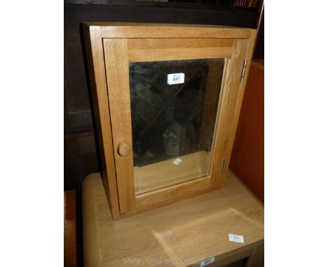 A light oak effect bathroom cabinet with mirrored door.