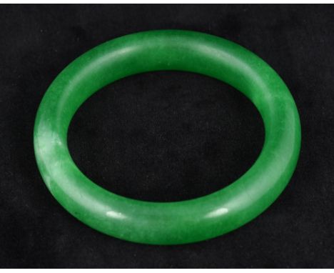 A Chinese apple green jade bangle
Of plain form.  8 cm diameter.  CONDITION REPORTS: Generally in good condition. 