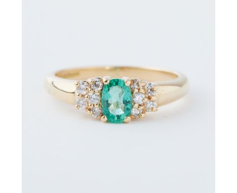 An 18ct yellow gold ring set with an oval cut emerald, approx. 0.42 carats, set with five small round brilliant cut diamonds 