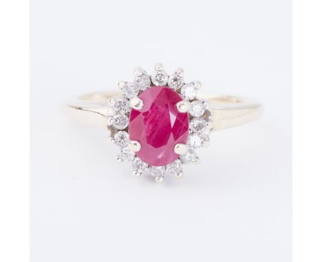 A 9ct yellow gold cluster ring set with a central oval cut ruby, approx. 0.75 carats, surrounded by small round brilliant cut