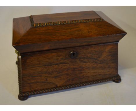 Regency period rose wood sarcophagus shaped tea caddy with bead decorated edges and brass lion head handles, the interior com