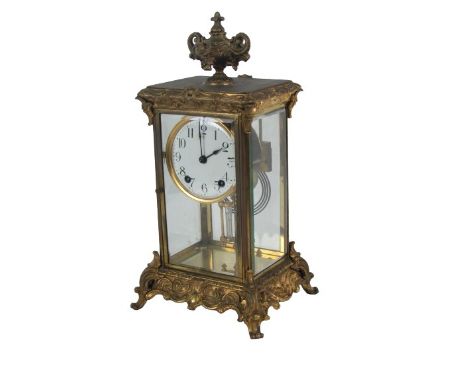 An early 20th Century American ormolu Mantle Clock, the top with ornate urn finial, the main body with glazed side, housing a