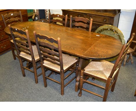 A mid 20th century oak dining suite , comprising of a drop leaf table, six rush seated ladder back dining chairs; a Court cup