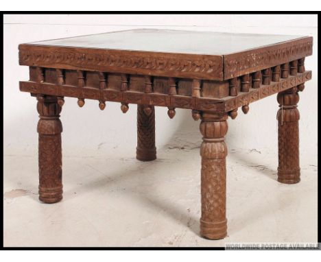 A 20th century Indian hard wood and brass studded square coffee table, having drop in glass panel, raised on carved legs. H41