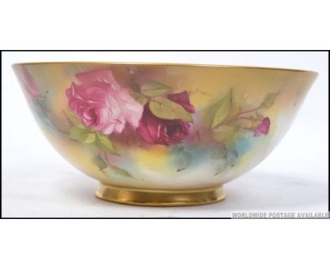 A Royal Worcester Ivory blush fruit bowl being handpainted with floral rose sprays, the puce markings to base for 1916-1948. 