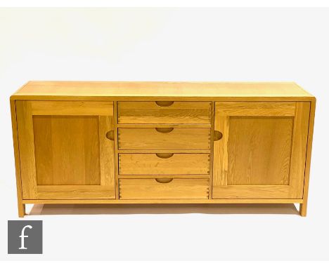 Ercol Furniture - A light oak Bosco range sideboard fitted with a central bank of four drawers flanked by a cupboard to eithe