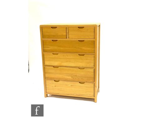 Ercol Furniture - A light oak Bosco range chest of two short over four long drawers, with curved finger joint detailing and r