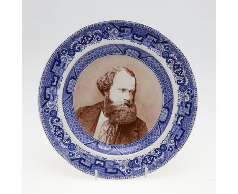 A pottery plate with dished centre with a portrait of Albert Smith in brown, looking to his left, in a blue transfer printed 