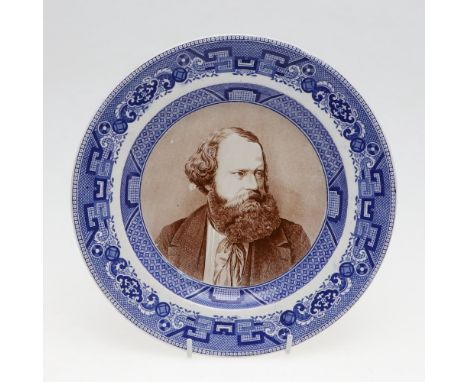 A pottery plate with dished centre with a portrait of Albert Smith in brown, looking to his left, in a blue transfer printed 