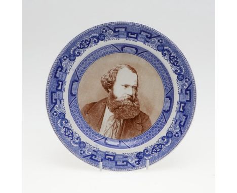 A pottery plate with dished centre with a portrait of Albert Smith in brown, looking to his left, in a blue transfer printed 