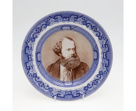 A pottery plate with dished centre with a portrait of Albert Smith in brown, looking to his left, in a blue transfer printed 