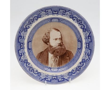 A pottery plate with dished centre with a portrait of Albert Smith in brown, looking to his left, in a blue transfer printed 