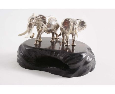 A CONTEMPORARY SOUTH AFRICAN MINIATURE SCULPTED FIGURE GROUP OF TWO BULL ELEPHANTS with resin tusks, on a carved ebony base, 