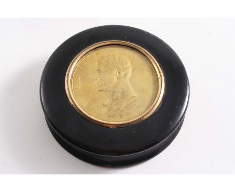 AN EARLY 19TH CENTURY LACQUERED WOODEN SNUFF BOX of circular form, the cover inset with a gilt-metal medallion depicting a po