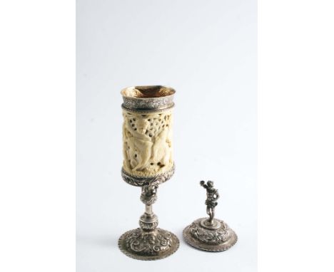 A 19TH CENTURY GERMAN STANDING CUP & COVER with a carved & pierced ivory sleeve around the bowl, embossed & chased borders an