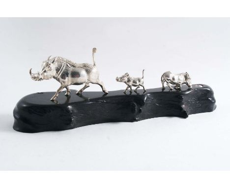 A CONTEMPORARY SOUTH AFRICAN MINIATURE SCULPTED GROUP OF THREE WARTHOGS on an ebony base, by Patrick Mavros of Zimbabwe, c.19