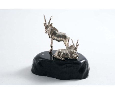 A CONTEMPORARY SOUTH AFRICAN MINIATURE SCULPTED GROUP OF TWO BUCK SABLE ANTELOPE, one standing, one sitting on an ebony base 