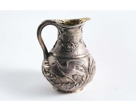 A VICTORIAN CHASED CREAM JUG of baluster form on a collet foot, decorated around the sides with foliate scrolls, Ho-ho birds 