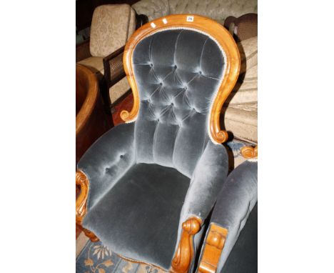 A Victorian mahogany framed button back armchair on turned legs with scrolled arms 