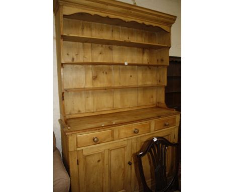 A pine dresser with shelves to the panelled back fitted with three drawers and two panel doors, 144cm 