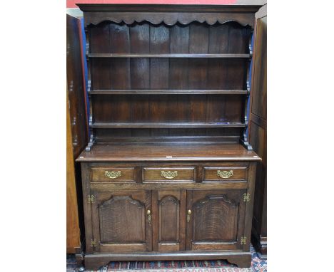 A 20th century oak dresser, outswept cornice above a shaped apron and three plate racks, the base with three short drawers ab