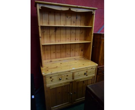 A 20th century pine dresser, oversailing cornice above two adjustable shelves, the base with two short drawers above a pair o