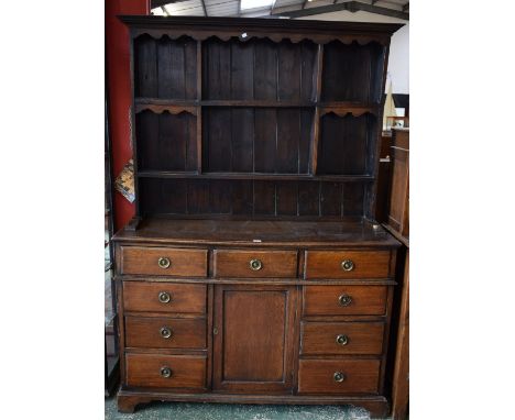 An early 20th century oak farmhouse dresser, outswept cornice above a shaped apron and an arrangement of segmented plate rack