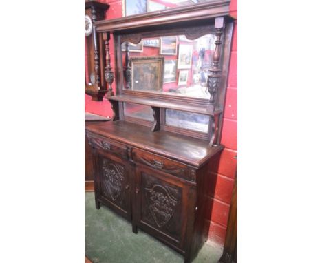 An Arts and Crafts style pine mirror-back sideboard, outswept moulded cornice above a shaped bevelled plate mirror, flanked b