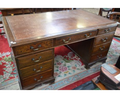 A 20th century oak writing desk, moulded rectangular top with inset tooled leather writing surface above three frieze drawers