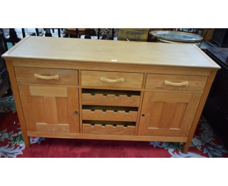 A Marks &amp; Spencer light oak sideboard, rectangular top above three drawers and a pair of cupboard doors each enclosing a 