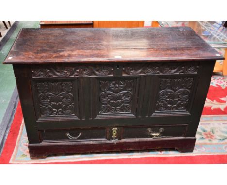 An 18th century oak blanket chest, of large proportions, moulded hinged rectangular top above a three panel front carved and 