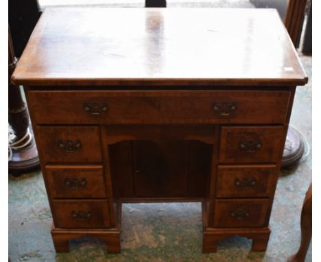 A 20th century walnut kneehole desk, of small proportions, shaped rectangular crossbanded quarter-veneered top above an arran
