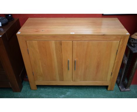 A contemporary oak sideboard, rectangular top above a pair of cupboard doors enclosing a shelf, 112.5cm wide