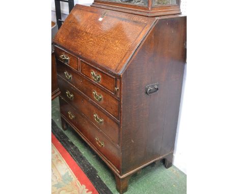 A 19th century oak bureau, of large proportions, fall front enclosing a small central door, small drawers and pigeon holes ab