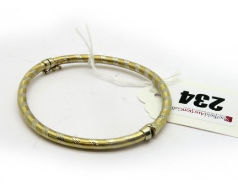 A Modern Bangle, of two colour textured twisted design, hinged, stamped "9kt".