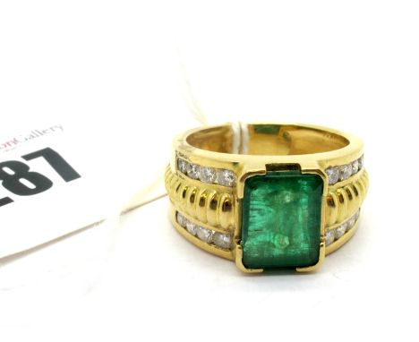 A Large Emerald and Diamond Set Dress Ring, the large (11x8.5mm) emerald corner set between wide textured and channel set sho