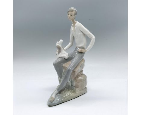 Glossy figure of a young man seated on an a rock with a dog on his lap. Dimensions: 6"L x 5"W x 10"HManufacturer: Nao by Llad